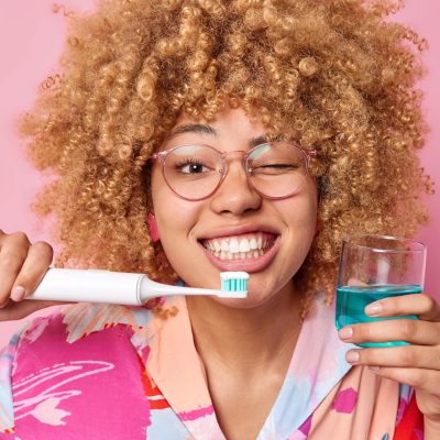 happy-young-woman-holds-glass-of-fresh-mouthwash-a-2022-12-21-15-03-48-utc-min